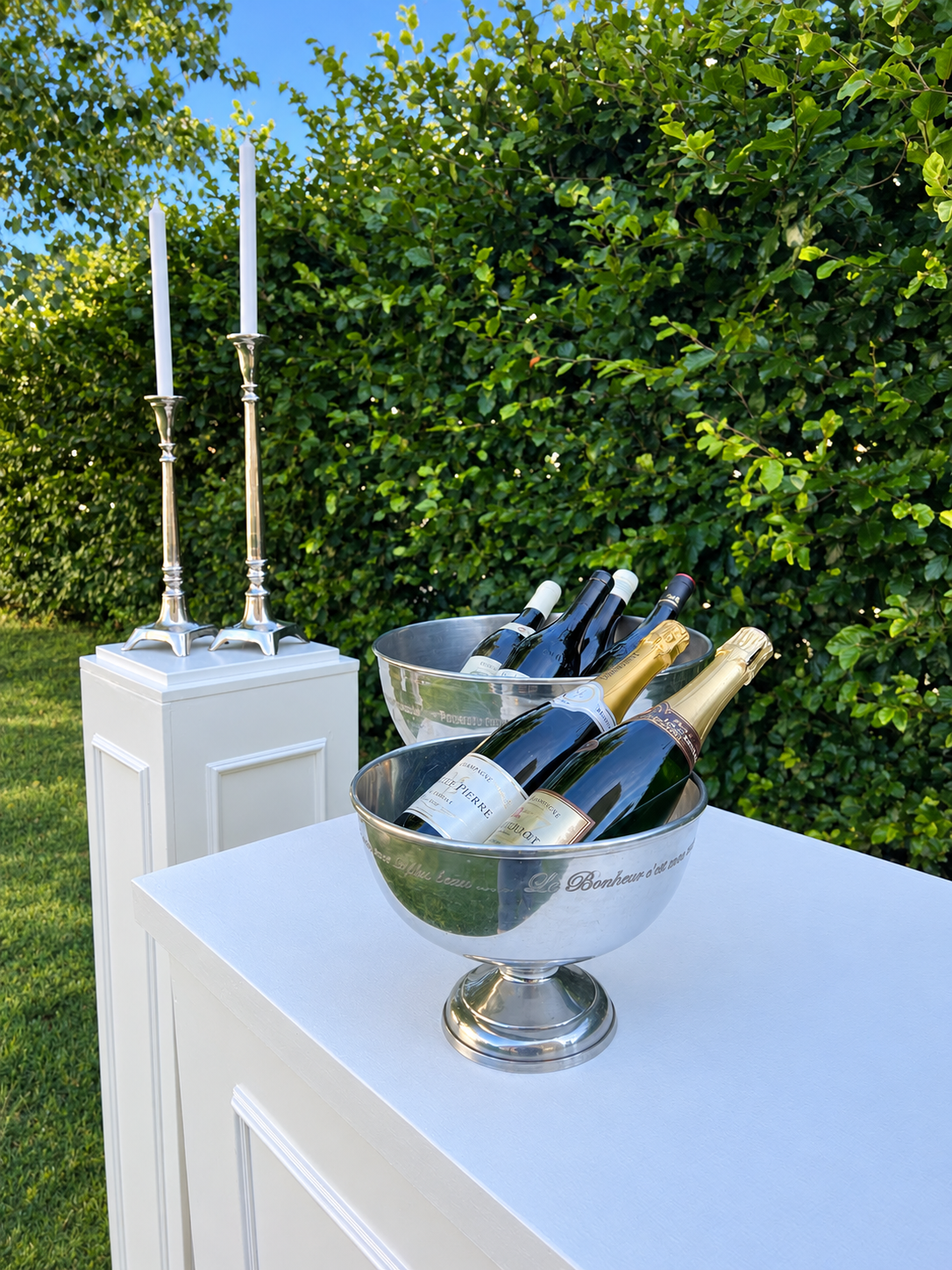 Champagnekjølere og sølvlysestaker på hvite sokler